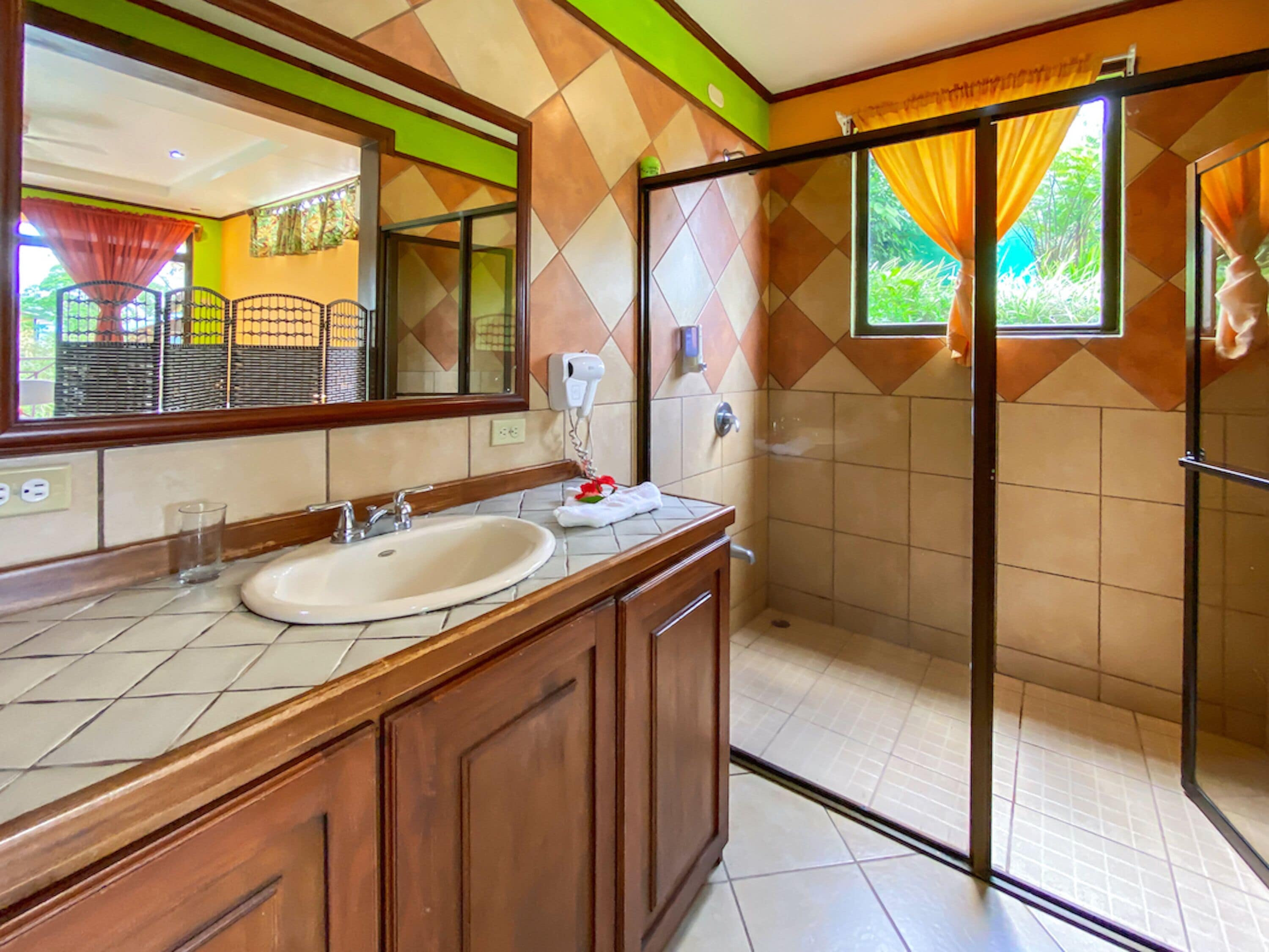 A bathroom with a sink, mirror, and shower area.