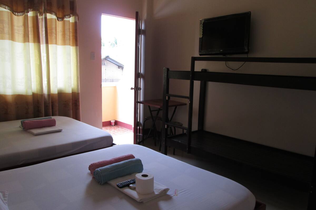 Una habitación de hotel con dos camas, un televisor y una litera.