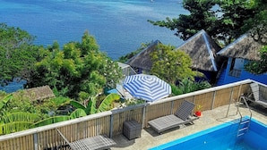 A swimming pool with a view of the ocean, lounge chairs, and a thatched-roof structure. - Boracay Water World Resort (Boracay Island)