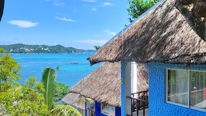 A blue house with a thatched roof, a view of the sea, and a tropical garden. - Boracay Water World Resort (Boracay Island)