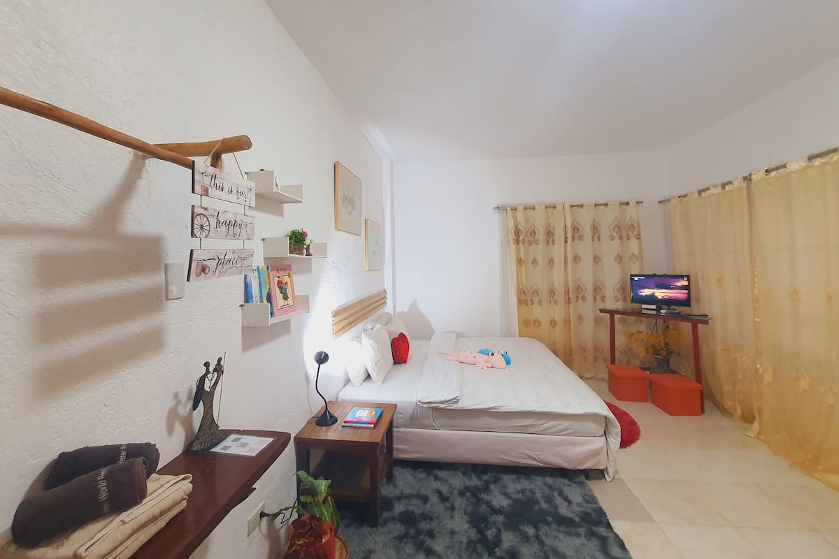 Une chambre à coucher avec un lit, une table de chevet, une télévision et un mur avec des étagères.
