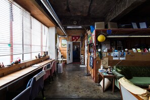 A room with a long wooden desk, a green sofa, and a cluttered wall with various items and decorations. - Urban Art Guesthouse (Seoul)