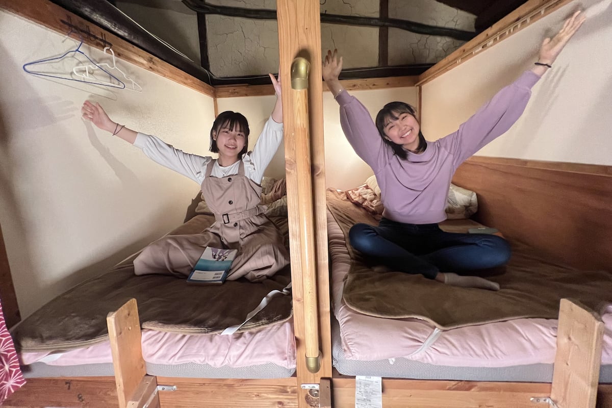 Een kleine kamer met houten wanden en twee stapelbedden, elk voorzien van een matras en kussens.