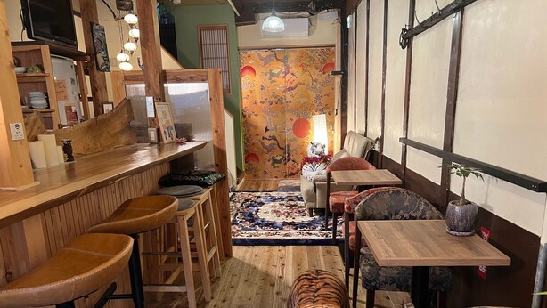 Ein Restaurantinneres mit Holztischen, einem Tiger-Plüschtier und einer traditionellen asiatischen Wandmalerei.