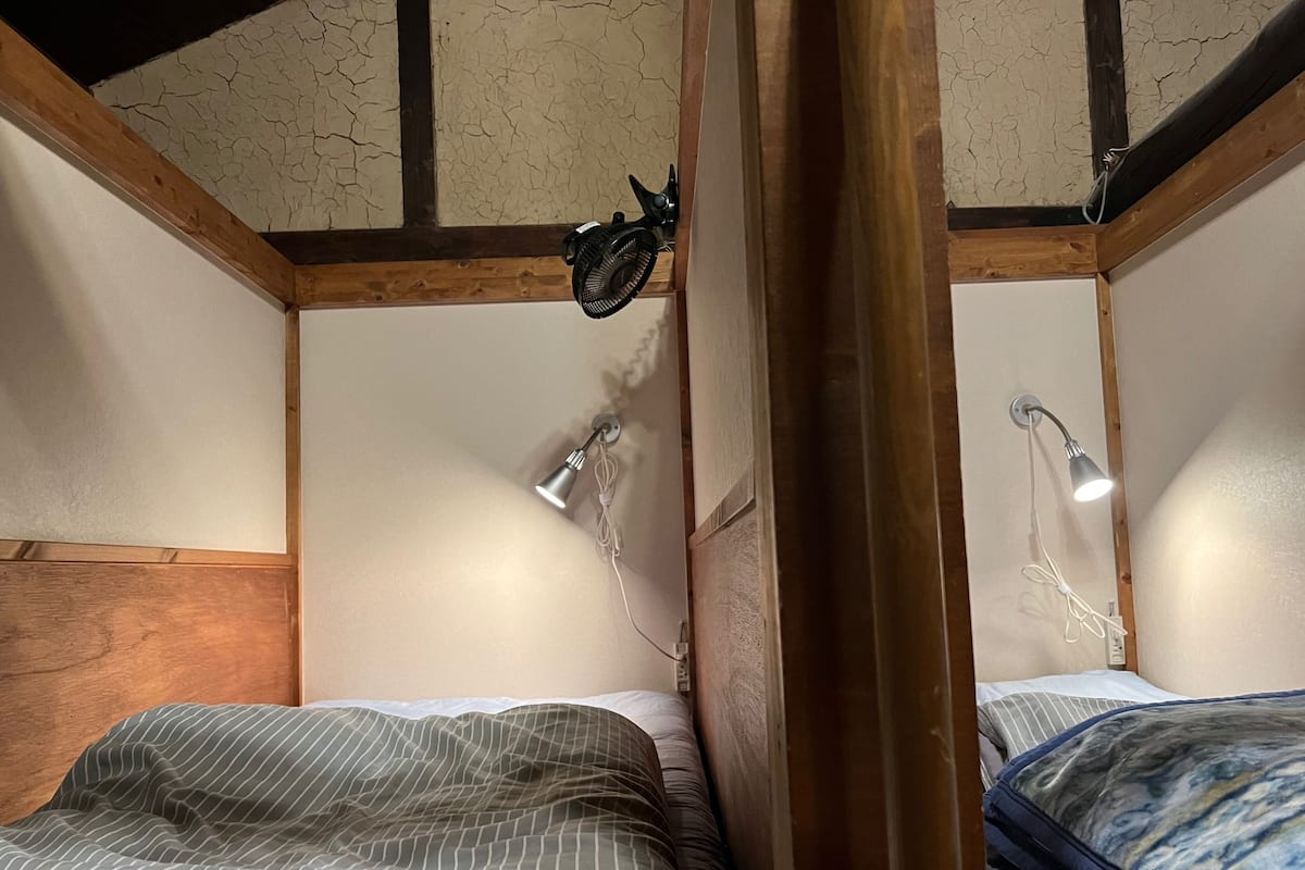 Een kamer met twee bedden, houten balken en plafondlampen.