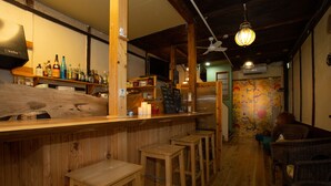 Eine Bar mit Holzhockern, Regalen voller Flaschen und einem Wandgemälde.