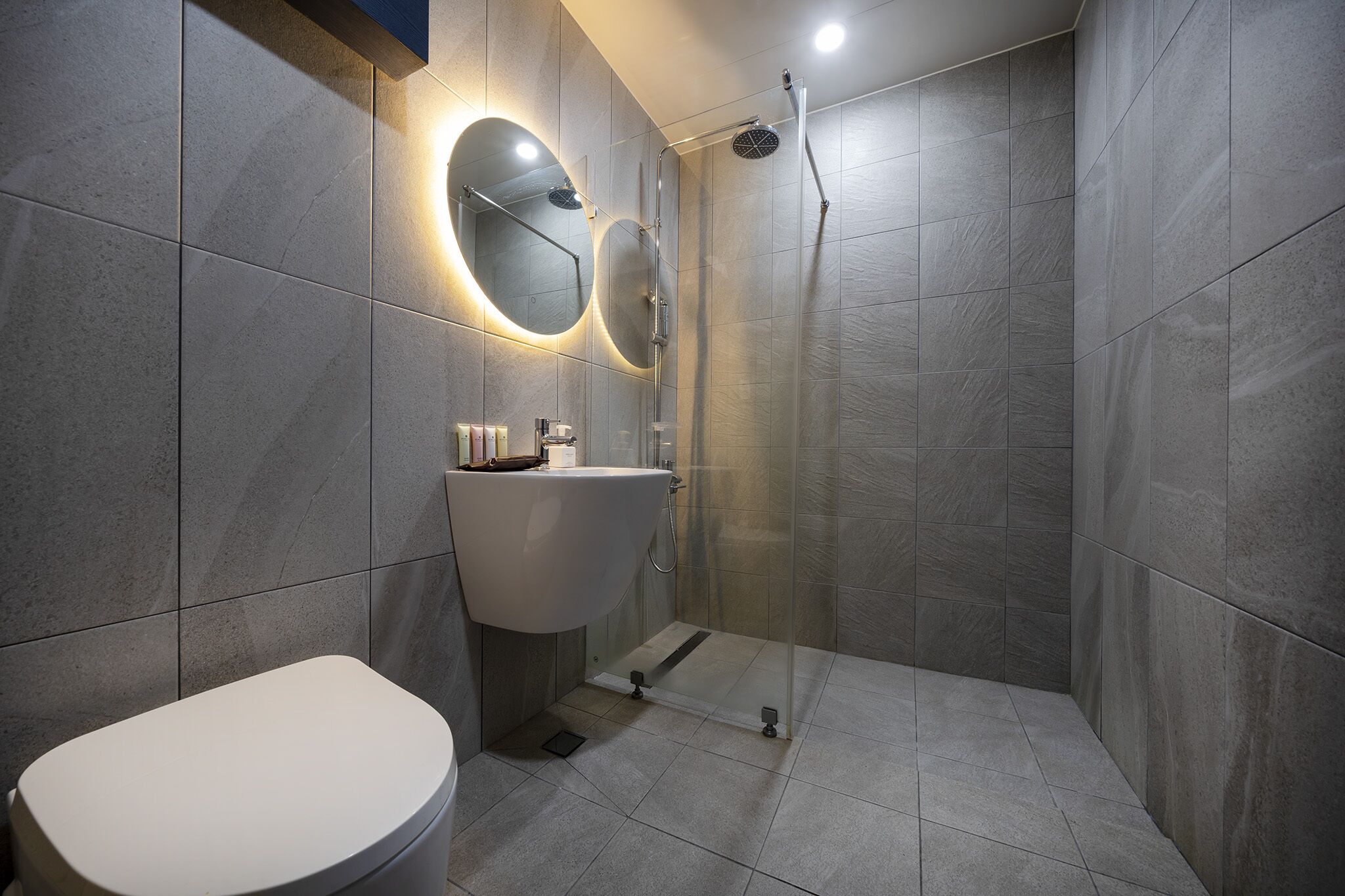 A modern bathroom with a toilet, sink, and glass-enclosed shower area.