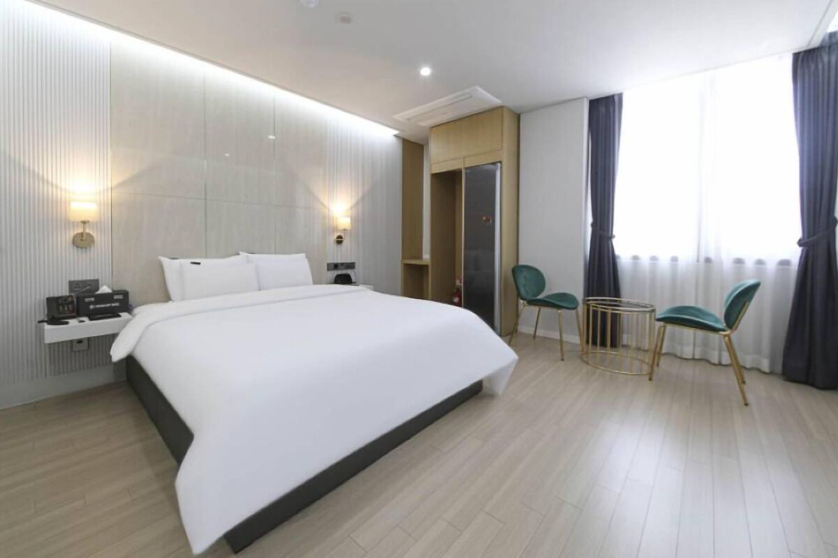Quarto de hotel moderno com uma cama grande, mesas de cabeceira, uma escrivaninha e duas cadeiras.