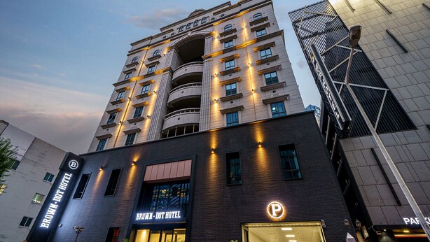 A multi-story hotel with a modern design, featuring a prominent entrance with a glass facade and a parking sign. - Browndot Gwangju Sangmu (Gwangju)