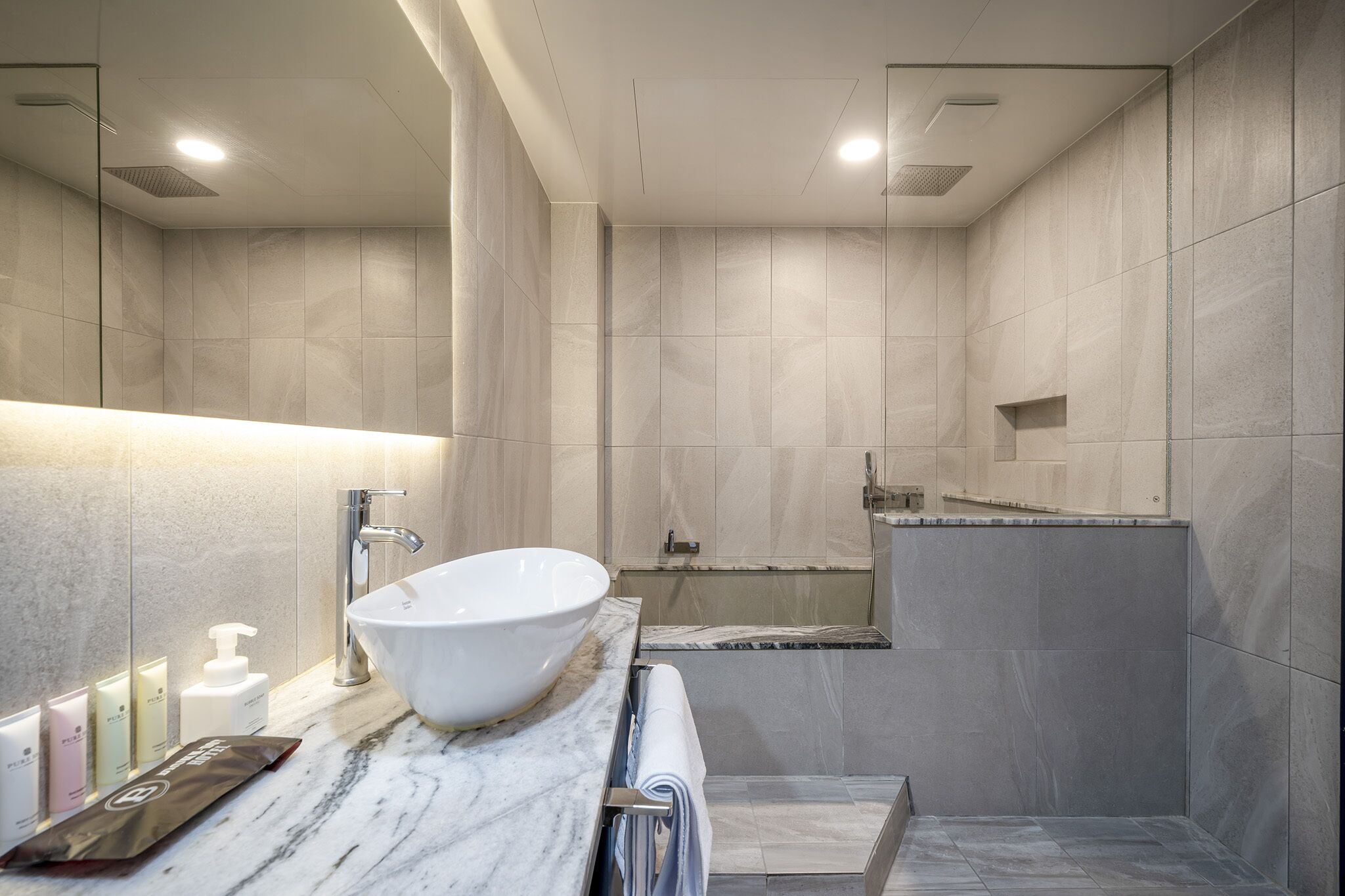 Une salle de bain moderne avec un grand lavabo blanc, un miroir et un espace douche.