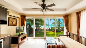 A spacious living room with a TV, a sofa, and a ceiling fan.