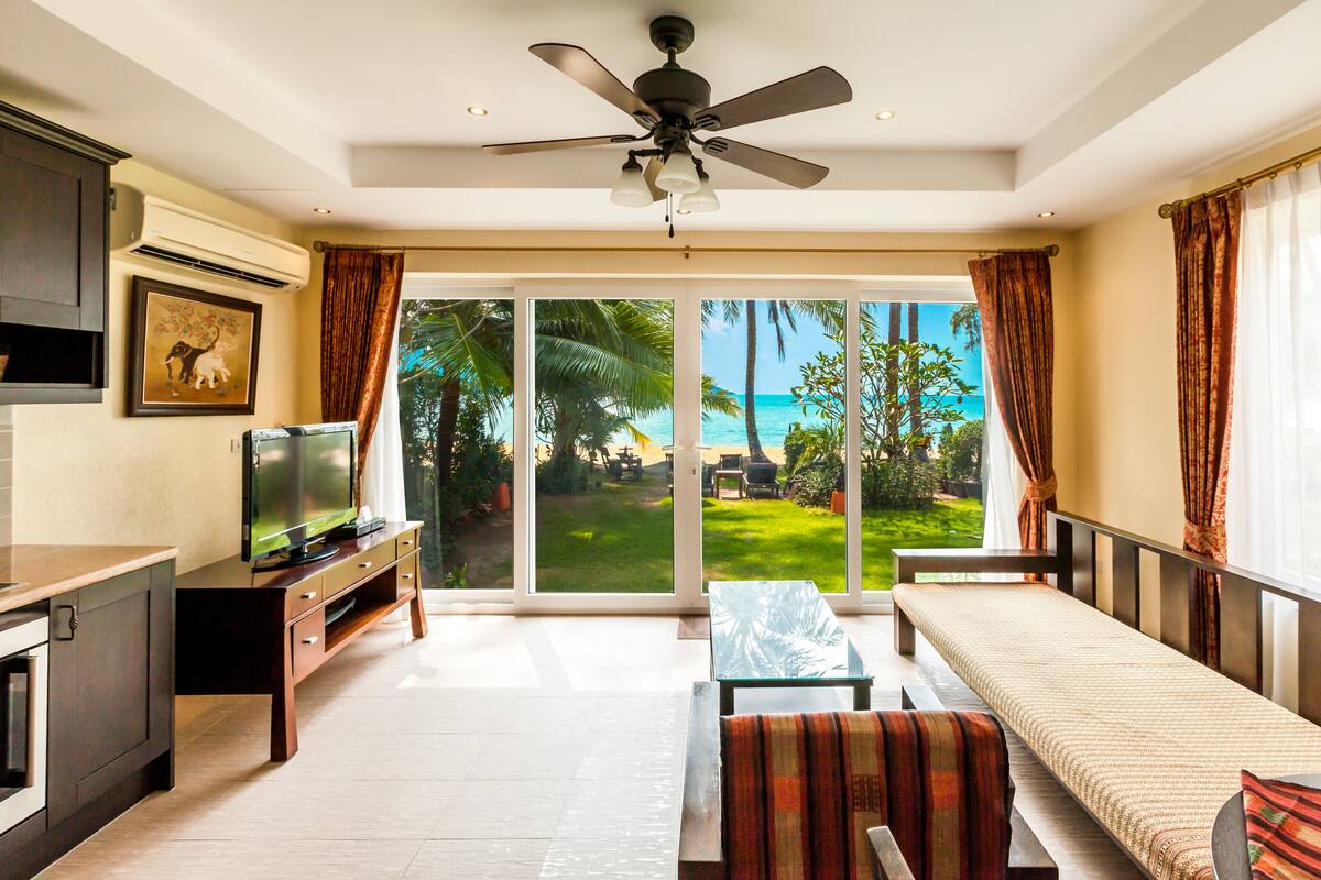 A spacious living room with a TV, a sofa, and a ceiling fan.
