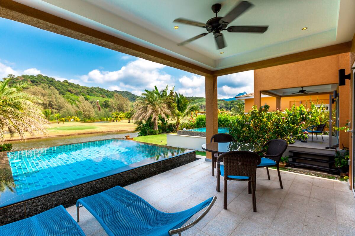 A pool area with a view of a golf course and hills.