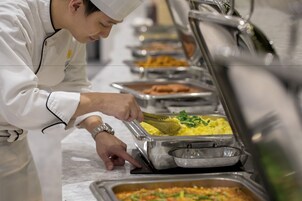 Un buffet con múltiples fuentes de comida, incluyendo huevos revueltos y un plato de verduras.