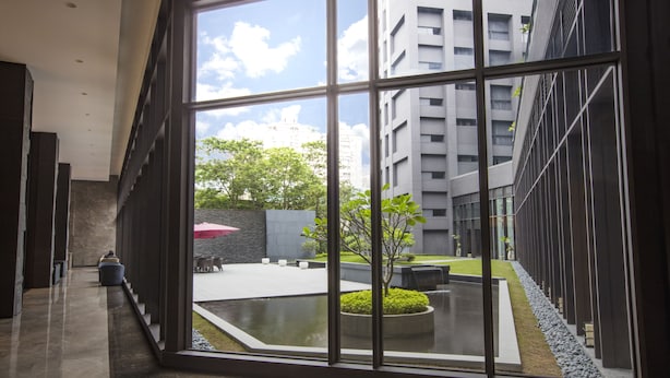 Un bâtiment moderne doté d’une cour intérieure agrémentée d’un petit élément décoratif aquatique, d’espaces pour s’asseoir et de verdure.