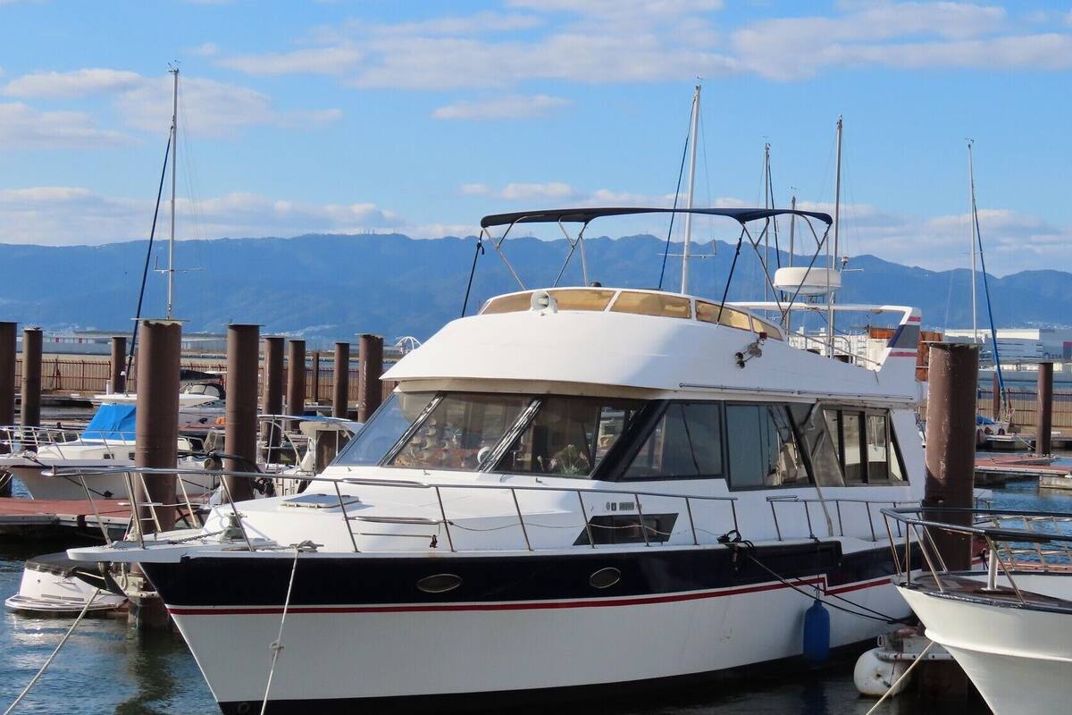 Un port de plaisance avec des bateaux amarrés, un ciel dégagé et des montagnes en arrière-plan.