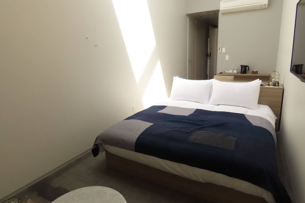 Une chambre d’hôtel avec un lit, une table de chevet et une petite table ronde.