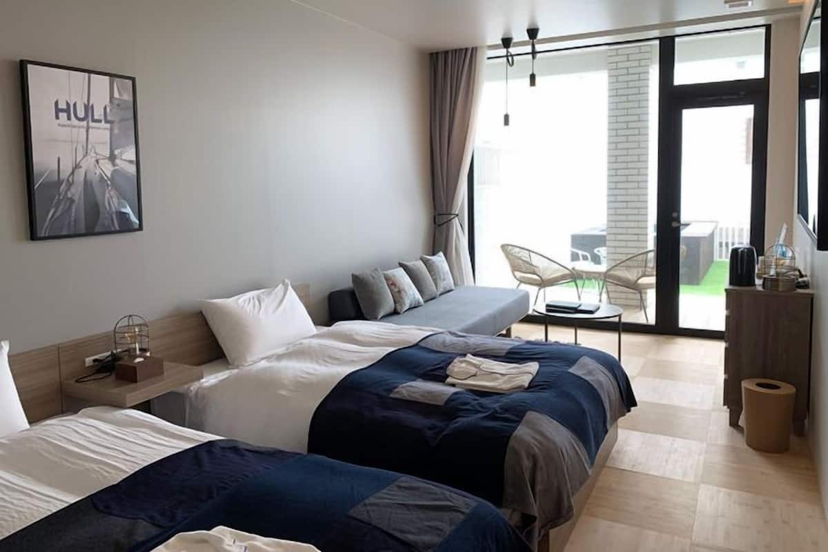 Une chambre d’hôtel avec deux lits, une grande fenêtre, une vue sur l’extérieur et un fauteuil près de la fenêtre.