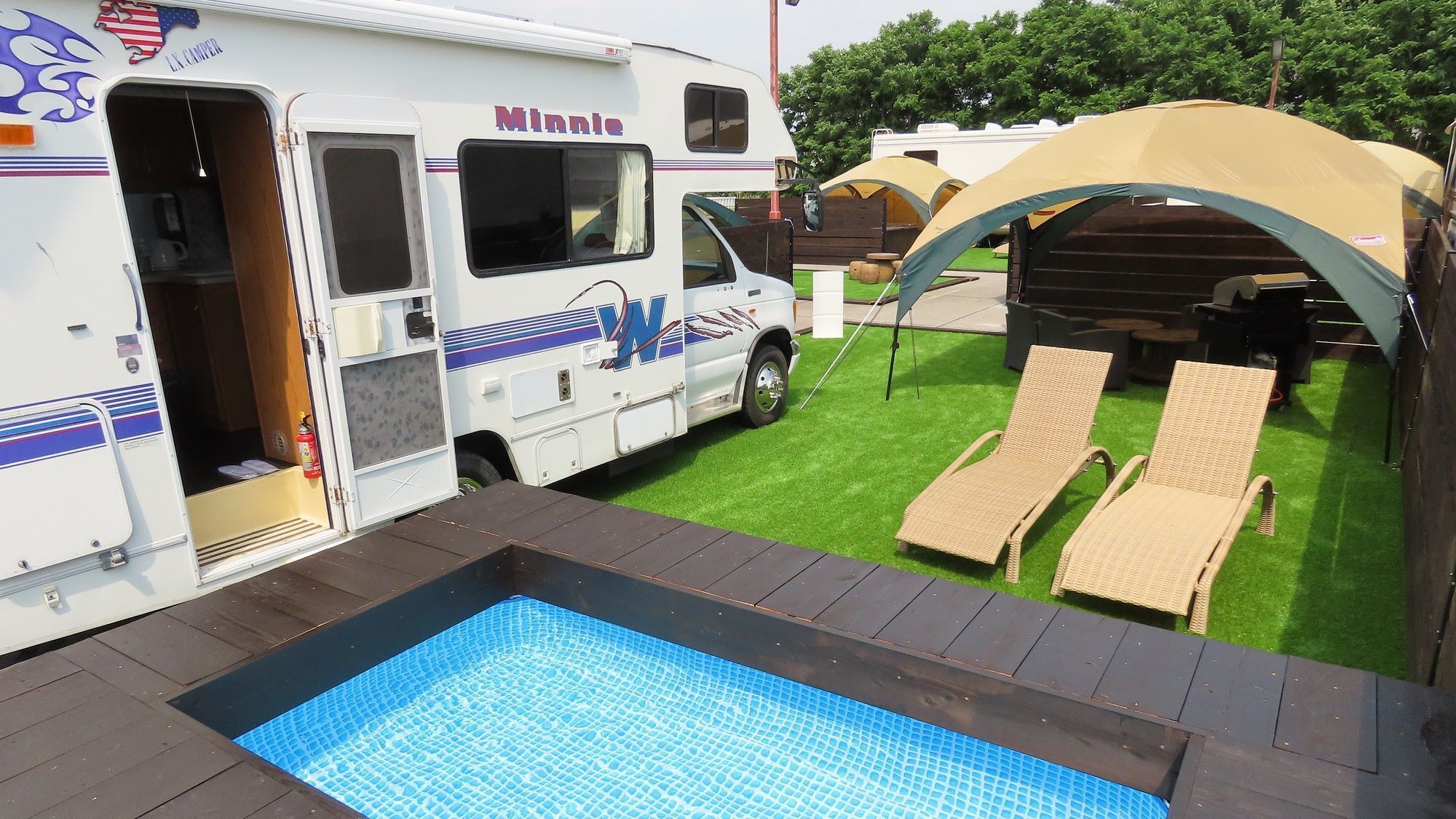 Un véhicule récréatif équipé d’une piscine, de chaises longues et d’une tente.
