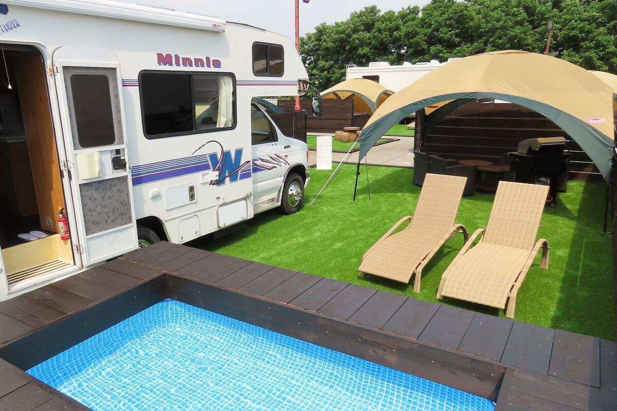 Un véhicule récréatif équipé d’une piscine, de chaises longues et d’une tente.