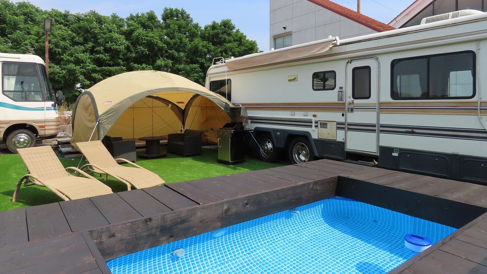 Un espace de camping équipé d’une piscine, de chaises longues et d’une tente couverte.