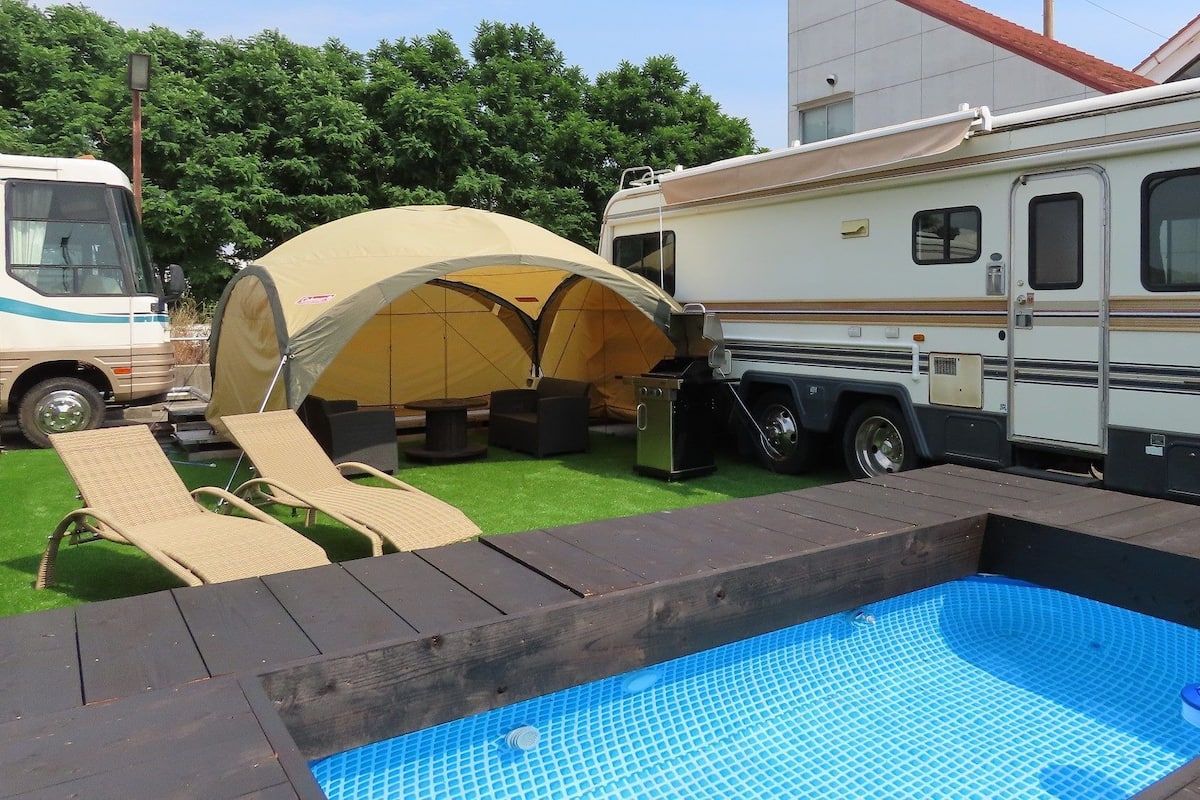 Un espace de camping équipé d’une piscine, de chaises longues et d’une tente couverte.