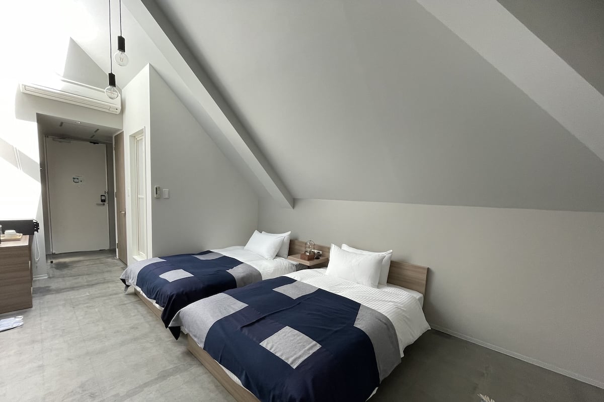 Une chambre moderne avec deux lits, une tête de lit en bois et un plancher en béton.