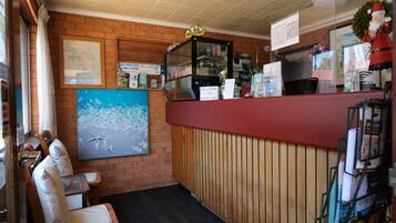 A reception area with a brick wall, wooden paneling, a red counter, and a map on the wall.