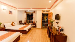 Habitación de hotel con dos camas, un televisor, un armario de madera y una mesita con un florero.