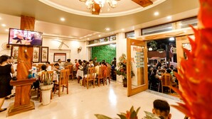 Un restaurante con mobiliario de madera, un candelabro y una pantalla de televisión.