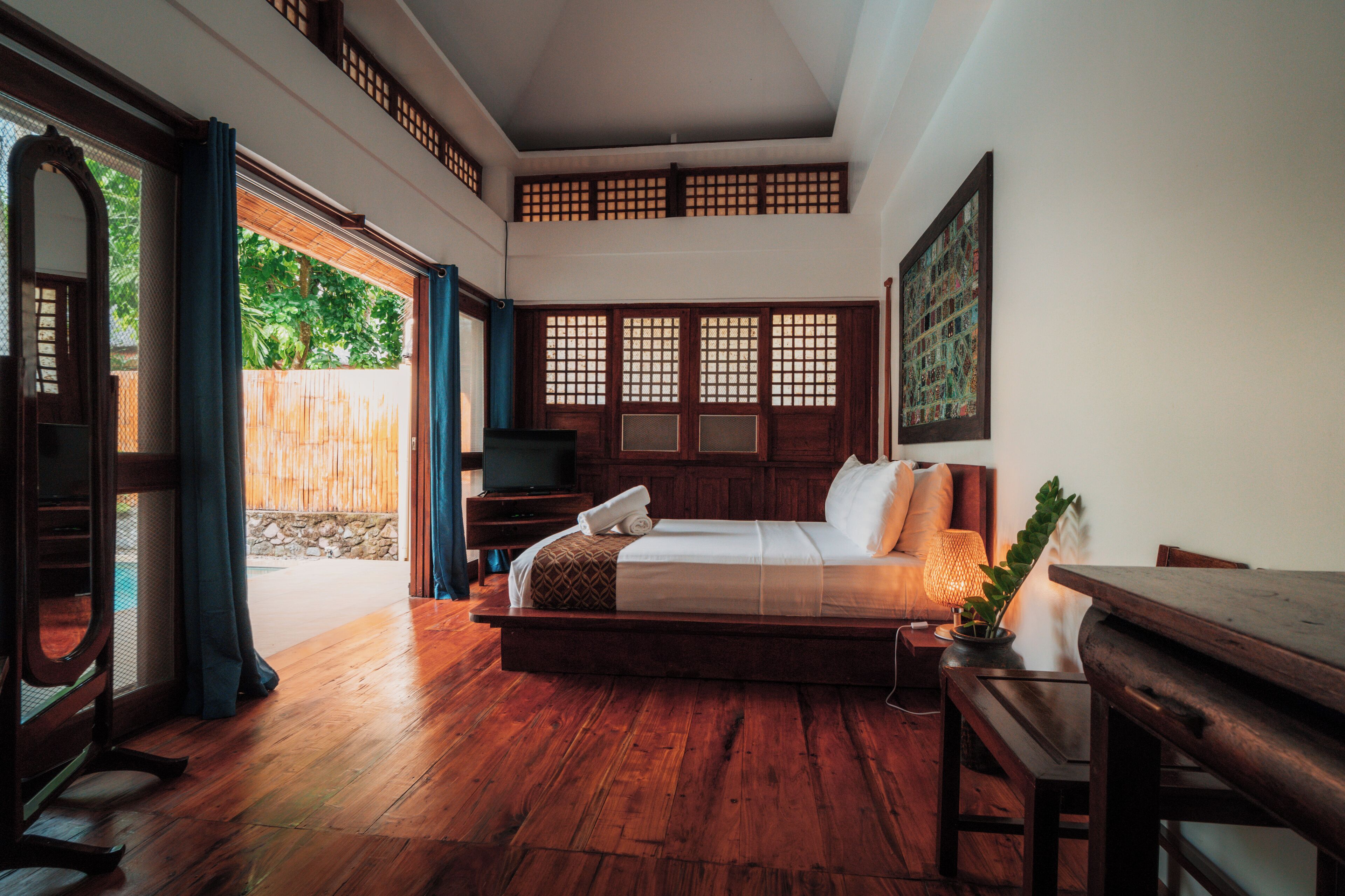 A traditional room with a bed, wooden flooring, and a view of the outdoors.