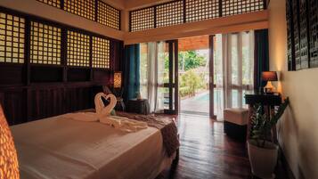 A hotel room with a large bed, a view of the garden, and a traditional wooden partition.