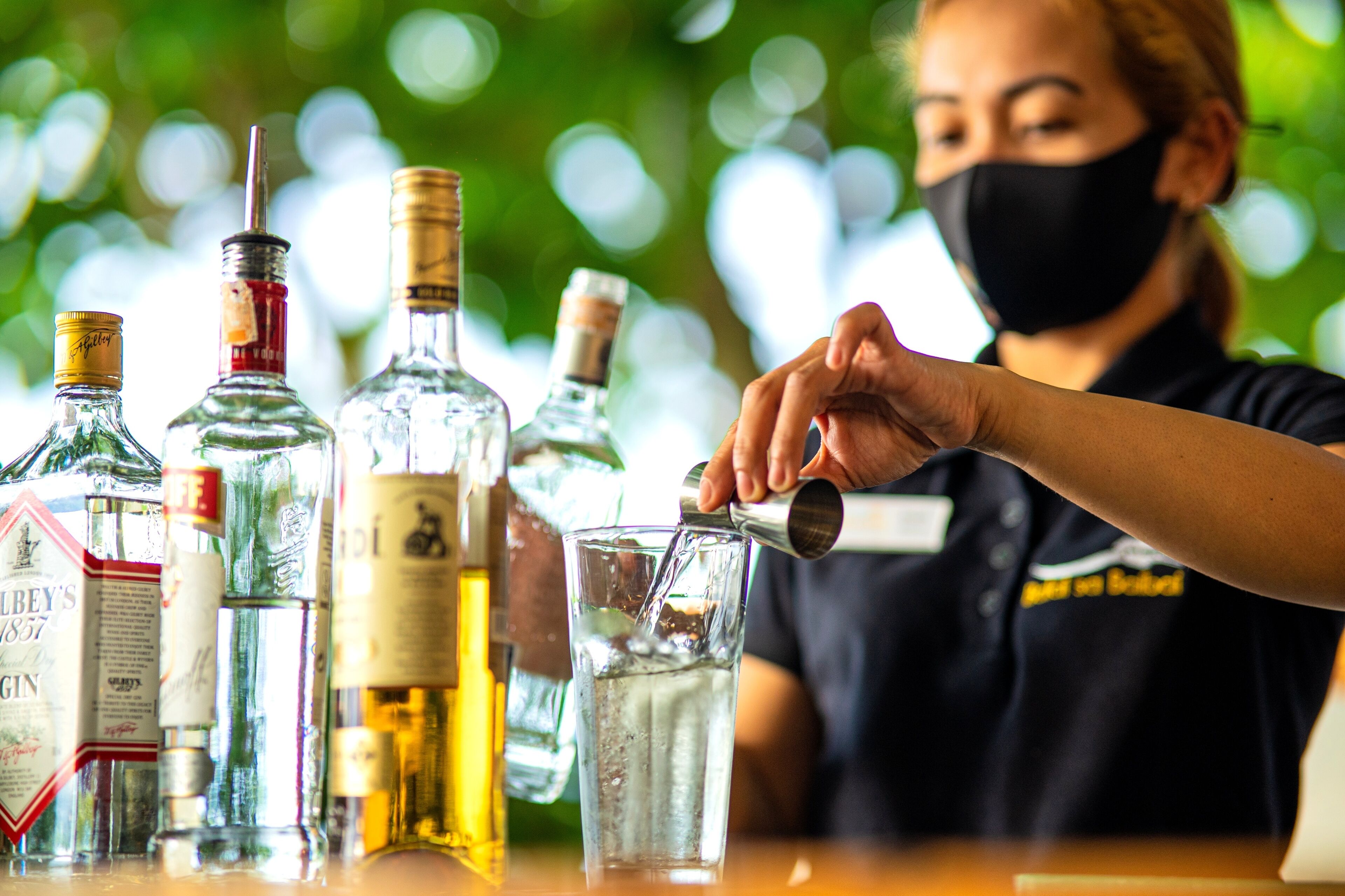 A bartender pouring a drink from a bottle into a glass.