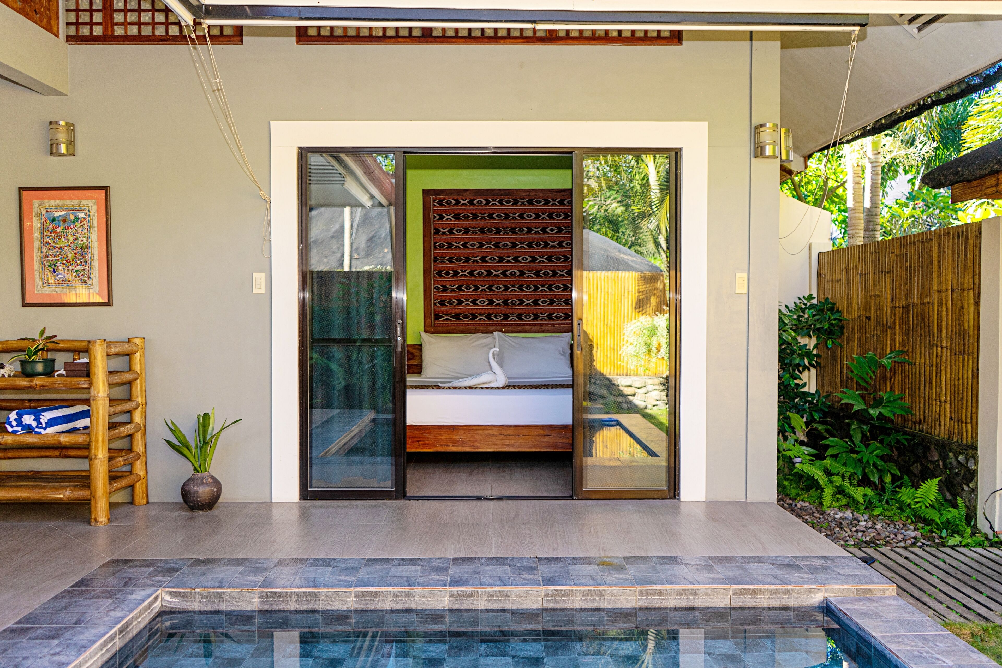 A modern bathroom with a glass shower enclosure, a wooden door, and a small potted plant.