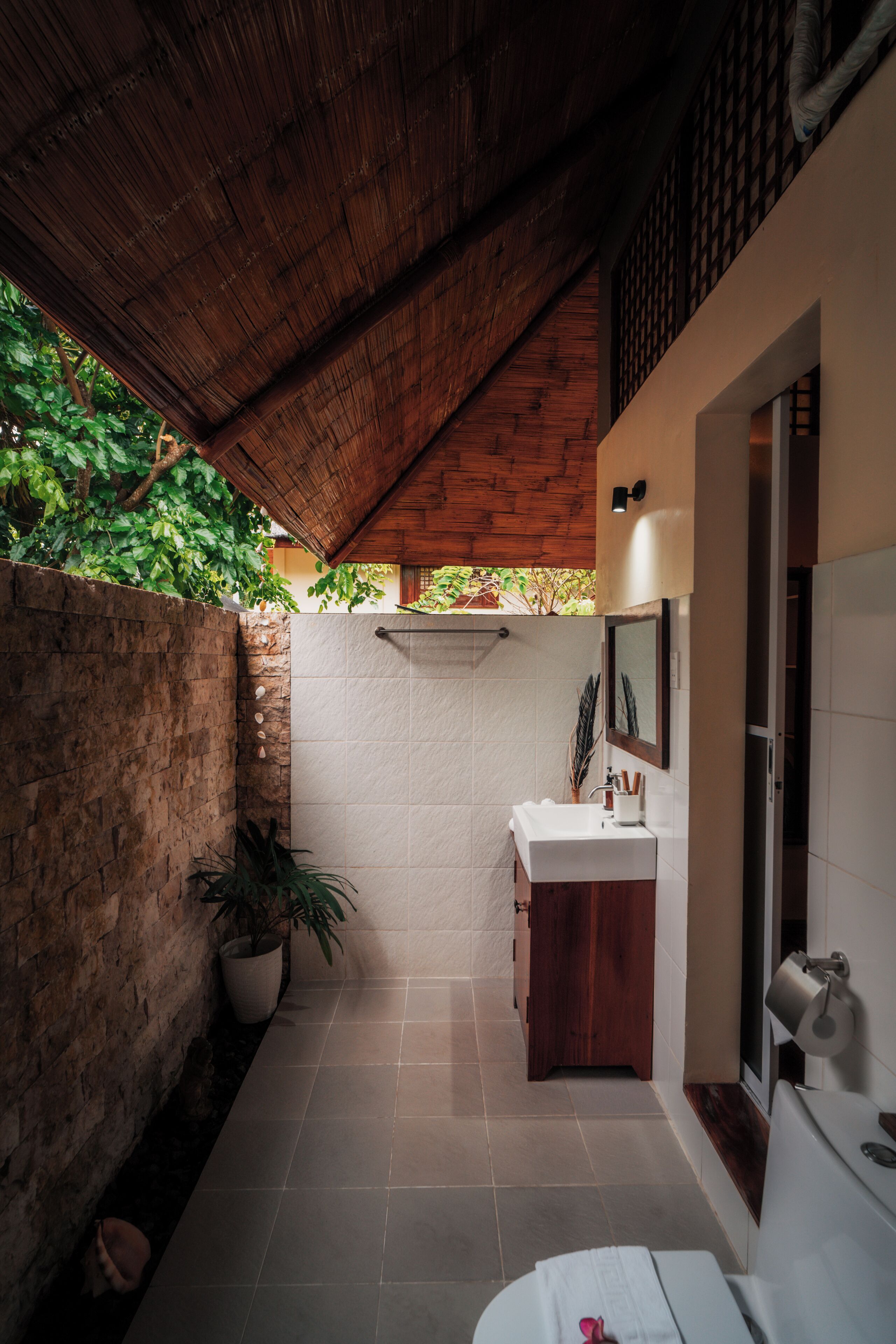 Une salle de bain moderne avec un plafond en bois, un lavabo blanc et un espace douche.