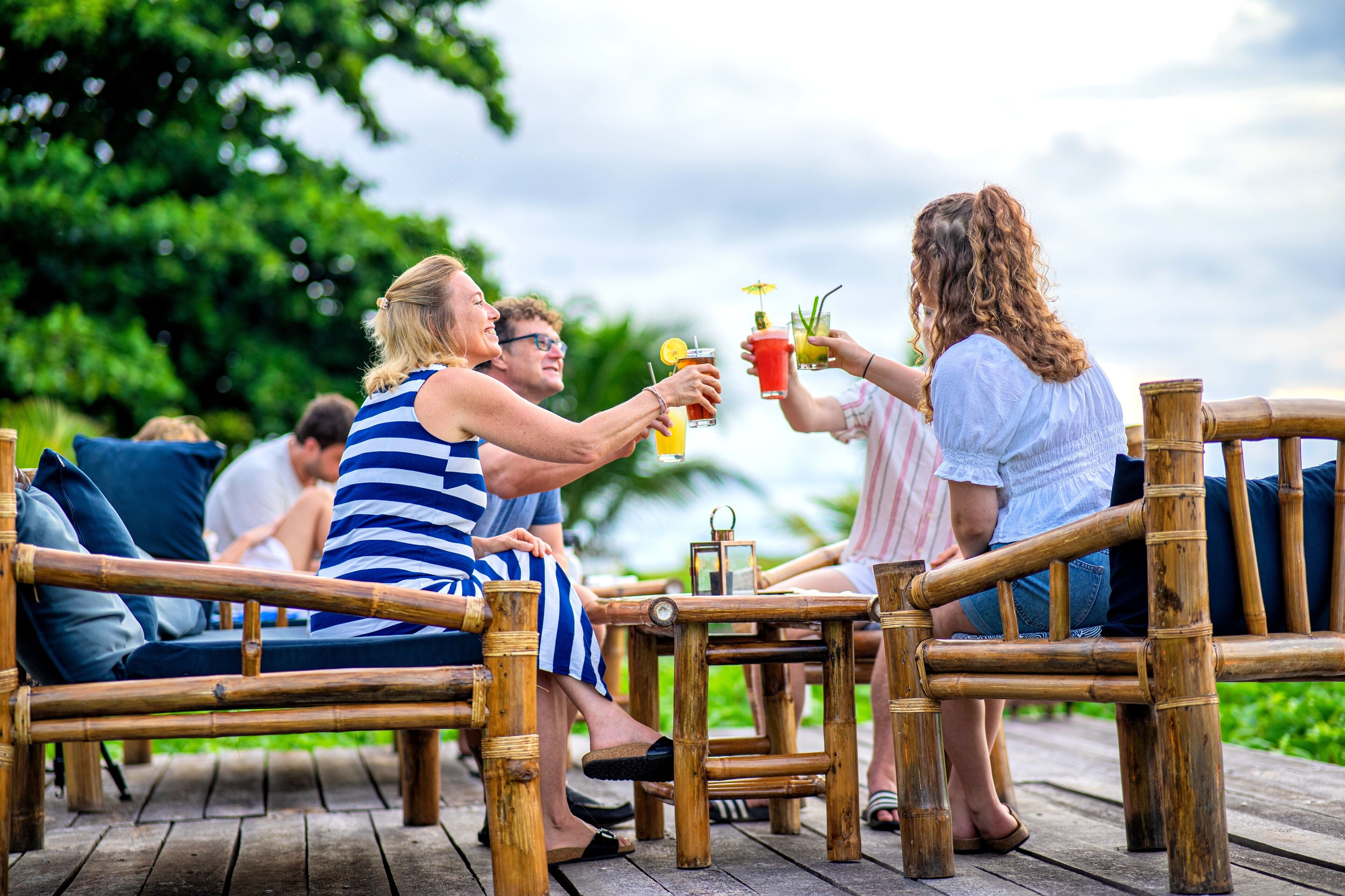 Une terrasse en bois avec des meubles en bambou et une petite table sur laquelle sont disposées des boissons.