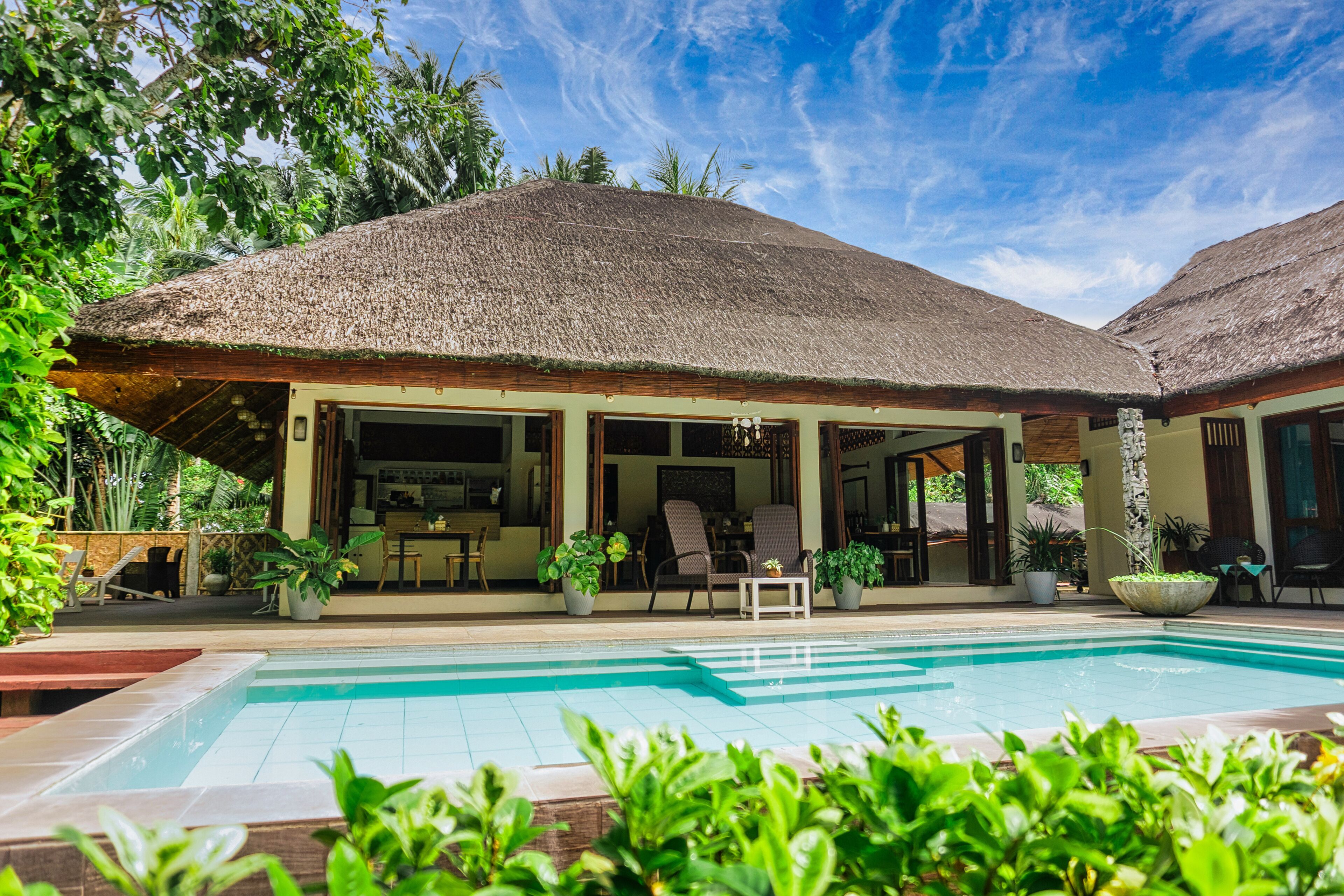 Ein Resort mit Pool, überdachter Außenbereich und üppiger Bepflanzung.