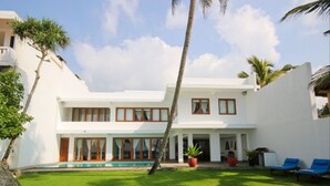 A two-story building with a swimming pool, a covered patio area, and a lawn. - Kixi Beach (Unawatuna)