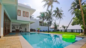 A modern house with a swimming pool, palm trees, and a clear sky. - Kixi Beach (Unawatuna)