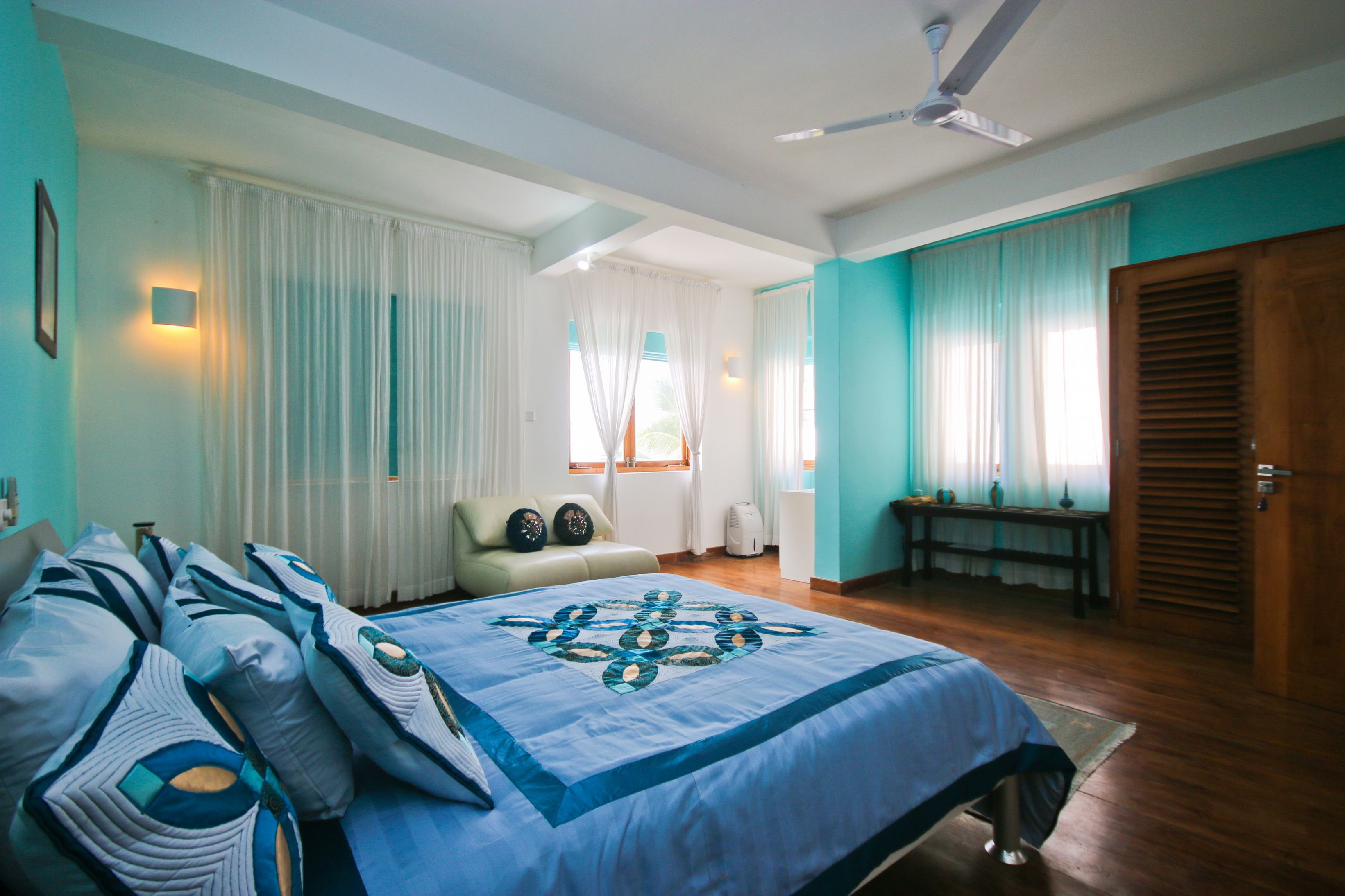 A bedroom with a bed, a chair, a table, and a door.
