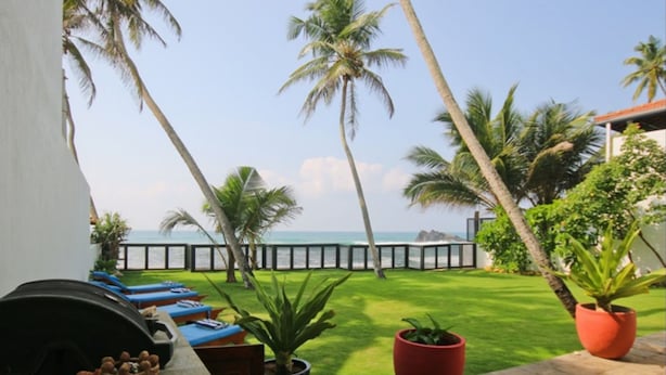 A patio with a view of the sea, palm trees, and a grassy area. - Kixi Beach (Unawatuna)