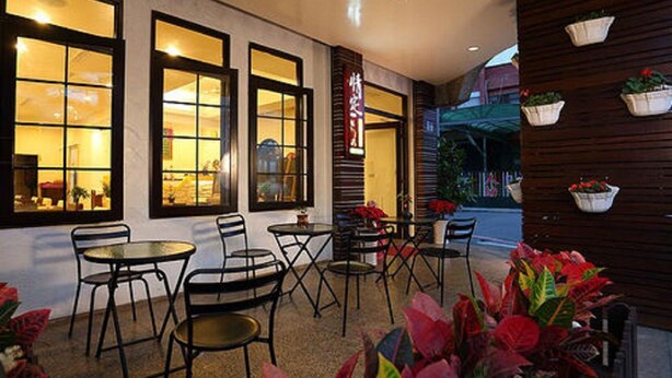 An outdoor cafe area with tables and chairs, large windows, and potted plants. - Love in Hualien (Hualien City)