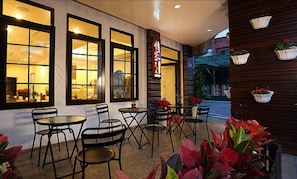 An outdoor cafe area with tables and chairs, large windows, and potted plants. - Love in Hualien (Hualien City)