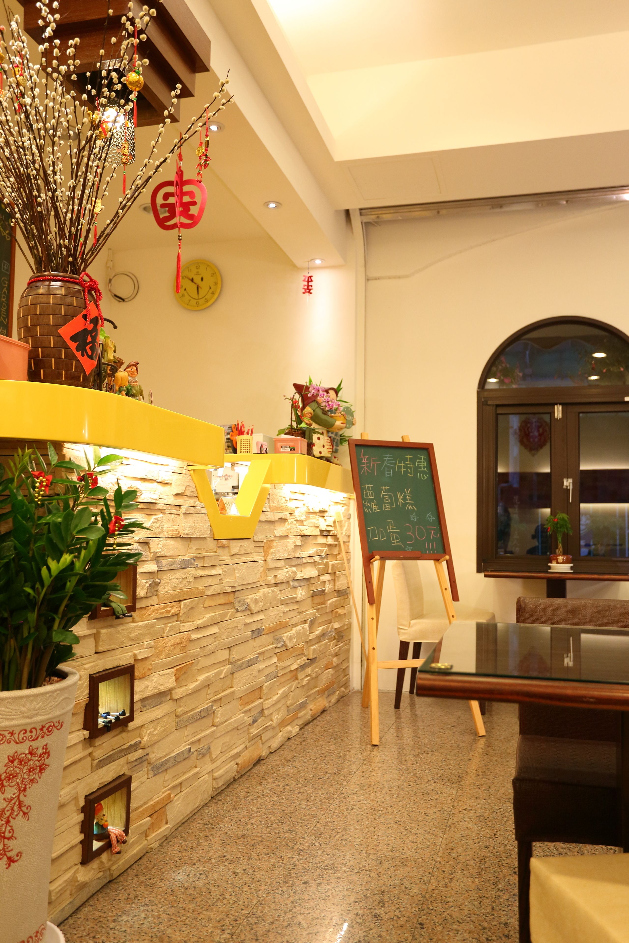 A reception area with a stone wall, a chalkboard menu, and a wooden reception desk.