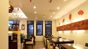 A restaurant with multiple tables and chairs, a ceiling fan, and decorative elements on the walls. - Love in Hualien (Hualien City)