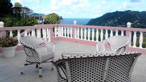 A balcony with wicker furniture and a view of the sea and hills. - Top Ranking Guesthouse (Speyside)