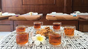 A room with two beds, each with a patterned bedspread and pillows, and a table with glasses of tea and snacks. - Infinity Guesthouse (Koh Tao)