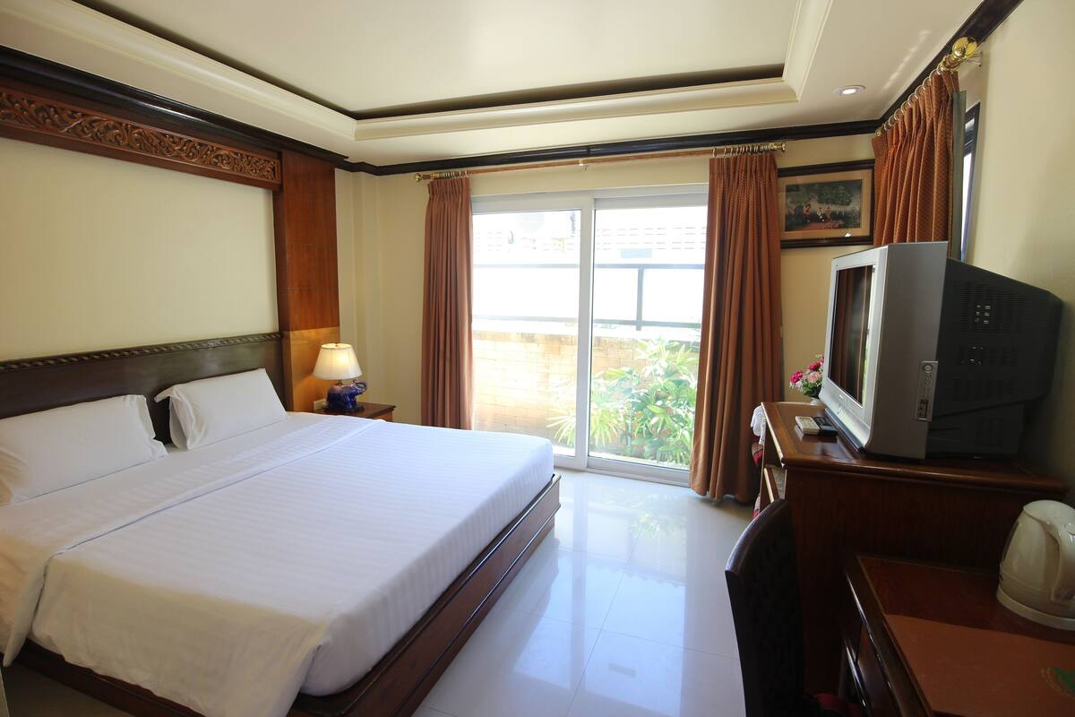 Une chambre d’hôtel avec un grand lit, une télévision, un bureau et une vue sur l’extérieur par la fenêtre.