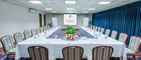 A conference room with a long table, chairs, and a floral centerpiece.