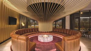 A circular seating area with a central fire feature, surrounded by a curved wall with a wooden finish.
